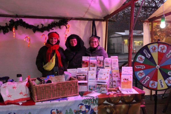 Drei Menschen am Stand auf dem Weihnachtsmarkt